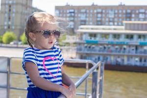 petite fille mignonne se reposant sur un bateau de luxe naviguant dans la grande ville photo