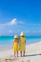 vue arrière de deux petites filles mignonnes regardant la mer sur la plage blanche photo