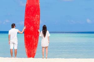 jeune couple avec planche de surf rouge pendant les vacances tropicales photo