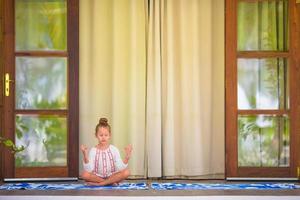 petite fille faisant des exercices de yoga sur la terrasse à l'extérieur photo