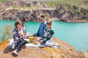 jeunes parents et enfants en pique-nique après une randonnée en montagne. belle vue sur le lac bleu photo