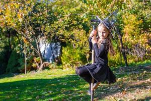 adorable petite fille en costume de sorcière d'halloween s'amusant sur un balai photo