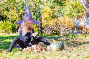 bonne petite sorcière s'amuse dehors à halloween. La charité s'il-vous-plaît. photo