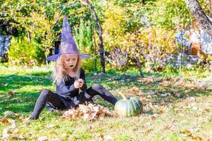 bonne petite sorcière s'amuse dehors à halloween. La charité s'il-vous-plaît. photo