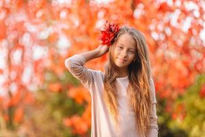 portrait d'une adorable petite fille au bouquet de feuilles jaunes à l'automne photo