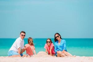 famille de quatre personnes faisant un château de sable sur une plage blanche tropicale photo