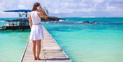 jeune femme parlant au téléphone pendant les vacances à la plage tropicale photo