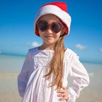 petite fille adorable en bonnet rouge sur la plage tropicale photo