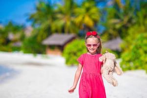 adorable petite fille jouant avec un jouet en peluche sur la plage photo