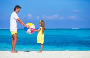 heureux père et fille jouant avec le ballon s'amusant en plein air sur la plage photo