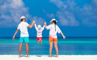 jeune famille de trois personnes sur la plage blanche pendant les vacances tropicales photo