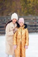 petite fille adorable avec sa mère patinant sur la patinoire photo