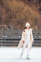 jeune fille souriante patinant sur une patinoire à l'extérieur photo