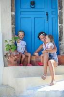 Jeune mère et sa fille assise sur le seuil de la vieille maison du village d'Emporio, Santorini, Grèce photo