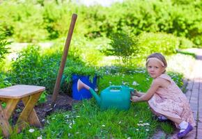 adorable petite fille avec arrosoir en plein air photo