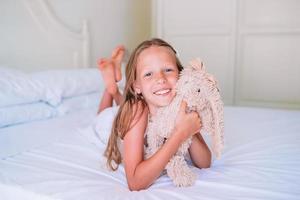 petite fille avec son lapin jouet regarde la caméra photo