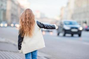 adorable petite fille prendre un taxi à l'extérieur dans une ville européenne photo