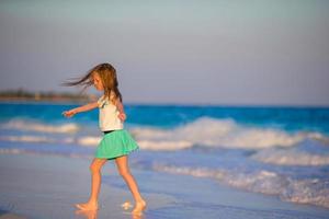 adorable petite fille à la plage s'amusant beaucoup en eau peu profonde photo