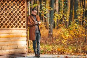 jeune homme dans le parc d'automne à l'extérieur écarta les bras photo