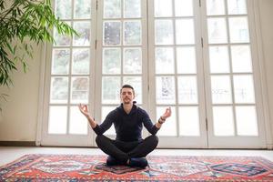 jeune homme assis en position du lotus à l'intérieur photo