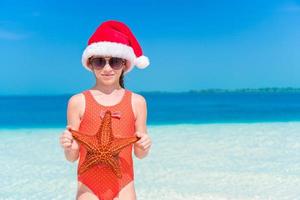 adorable petite fille avec des étoiles de mer sur une plage vide blanche photo