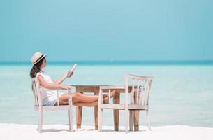 jeune femme lisant un livre pendant la plage maldivienne tropicale photo