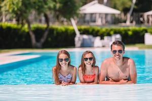 famille heureuse de quatre personnes dans une piscine extérieure photo