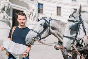 homme touriste avec un plan de la ville et un sac à dos dans la rue de l'europe. garçon caucasien regardant avec la carte de la ville européenne. photo