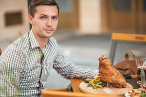 jeune homme en train de dîner dans un restaurant en plein air. photo