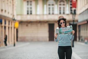 heureuse jeune femme avec un plan de la ville en ville. femme touristique de voyage avec carte à l'extérieur pendant les vacances en europe. photo