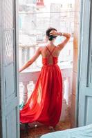 jeune femme séduisante en robe rouge sur le vieux balcon d'un appartement à la havane photo