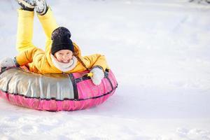 adorable petite fille heureuse faisant de la luge en hiver neigeux. photo