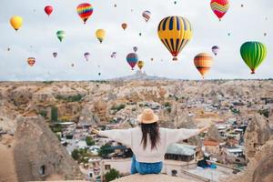 jeune femme heureuse au lever du soleil en regardant des montgolfières en cappadoce, en turquie photo