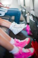 pieds de bébé en baskets sur le siège de l'avion petites filles adorables marchant à l'extérieur dans le champ de fleurs photo