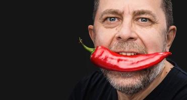 homme âgé avec du poivron rouge dans la bouche photo