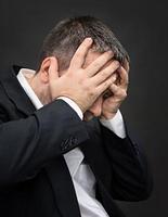 mal de tête. homme avec le visage fermé par les mains photo