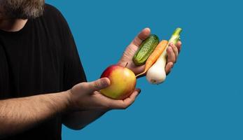 un homme en t-shirt noir tient des fruits et légumes photo