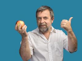 homme d'âge moyen souriant tenant une pomme rouge photo