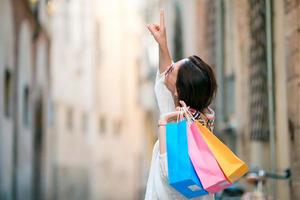 jeune fille avec des sacs à provisions dans une rue étroite en europe. portrait d'une belle femme heureuse tenant des sacs à provisions souriant photo
