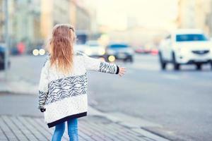 adorable petite fille prendre un taxi à l'extérieur dans une ville européenne photo