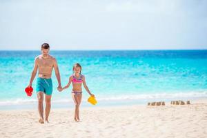 petite fille et papa heureux jouant sur la plage photo