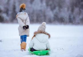 adorables petites filles heureuses faisant de la luge en hiver neigeux. photo