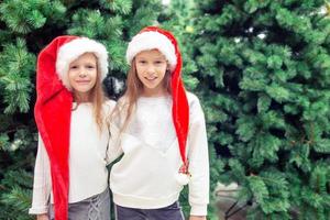 petites filles heureuses près de la branche de sapin dans la neige pour le nouvel an. photo