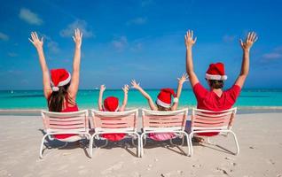 famille heureuse de quatre personnes en chapeaux de noël pendant les vacances tropicales photo