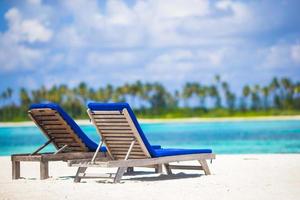 chaises longues avec sac et chapeau sur la plage blanche tropicale photo