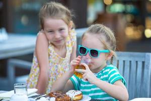 adorables petites filles prenant leur petit déjeuner au café en plein air photo