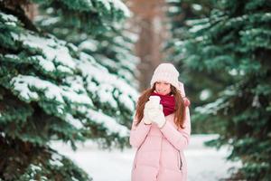 une fille heureuse profite de l'hiver et de la neige à l'extérieur lors d'une belle journée d'hiver photo