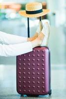 jambes féminines en gros plan, chapeau et bagages à l'intérieur de l'aéroport. passager d'une compagnie aérienne dans un aéroport en attente d'avion de vol photo