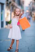 portrait d'une adorable petite fille marchant avec des sacs à provisions à l'extérieur dans la ville européenne. photo