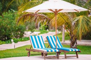 chaises longues blanches sur une belle plage tropicale aux maldives photo